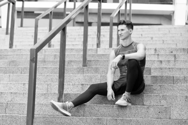 Portrait d'un homme sportif confiant. Jeune sportif assis à l'extérieur après un bon entraînement de jogging. Jeune homme en tenue de sport. se détendre après l'entraînement. Il est assis dans les escaliers. Pensif mec fort assis — Photo