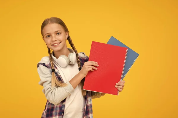 Z powrotem do szkoły. korzystać z notebooka lub książki. Lekcje do egzaminu. znaleźć inspirację w książce. Podoba mi się nauka. Pewna swojej wiedzy. Mały dzieciak w słuchawkach z notatnikiem. dziecko gotowe do nauki — Zdjęcie stockowe