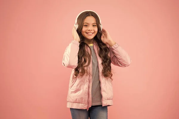 행복 한 어린이는 잘 듣는 것을 좋아한다. 여자 애가 분홍색 이어폰을 쓰고 있어. 소리의 진동. 음악과 기술. 오디오 소리. 재미와 오락. 계속되는 음악 — 스톡 사진
