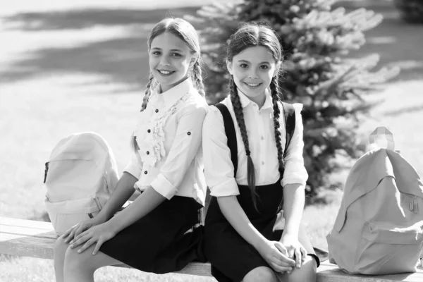 Exams. happy childrens day. childhood hapiness. two sisters in school uniform outdoor. ready for holidays. happy teen kids carry backpack. back to school. small school girls walking in spring