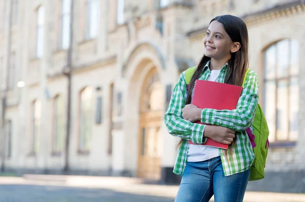 Glückliches Kind mit nachdenklichem Blick halten Bücher und Schultasche im Freien, Schulbildung, Kopierraum — Stockfoto