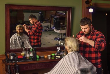 Hipster müşteri saçını kestiriyor. Berber ve müvekkil. Berber, sakallı adam berber dükkanında çalışıyor. Uzun sarı saçlı bir adam. Berber dükkanında profesyonel kuaför.