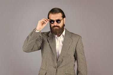 Ciddi sakallı adam. Pahalı takım elbiseli yakışıklı ve başarılı bir adam. O, beyaz gömlek ve gözlük takıyor. Takım elbiseli başarılı bir adam. İş adamı takım elbise giyer. resmi ofis yaşam tarzı