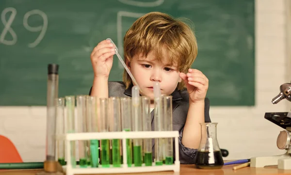 Εργαστήριο Χημείας. Πίσω στο σχολείο. Μικρό αγόρι στο χημικό ντουλάπι. Παιδί με εργαστηριακή ποδιά να μαθαίνει χημεία να πειραματίζεται με χημικά. Μικρό παιδί να μαθαίνει χημεία στο εργαστήριο. Στόχος μας είναι να βρούμε τη θεραπεία. — Φωτογραφία Αρχείου