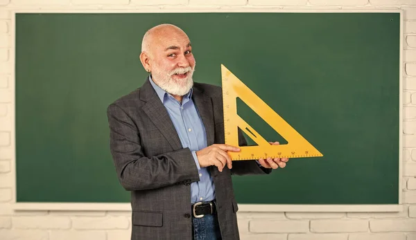 Understanding. bearded tutor man at blackboard. back to school. Math science concept with school lesson items. Mathematics at board. favorite subject. senior man teacher use math triangle tool