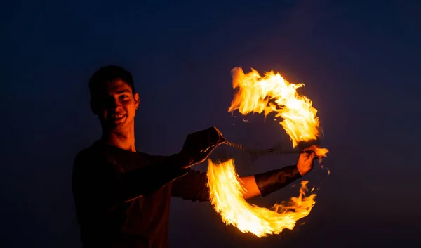 A fény és sötétség játéka. Tüzes forgószél éjjel. Boldog férfi pörgető égő poi. Tűz előadás. Poi spinning és flow art. Esti buli. Kültéri fesztivál. Ünneplés — Stock Fotó