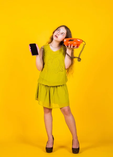 V obchodě. konverzace a komunikace. dospívající dívka s retro telefon a smartphone. dětská móda. Šťastné dětství. roztomilé dítě na žlutém pozadí. nová technologie v moderním životě — Stock fotografie