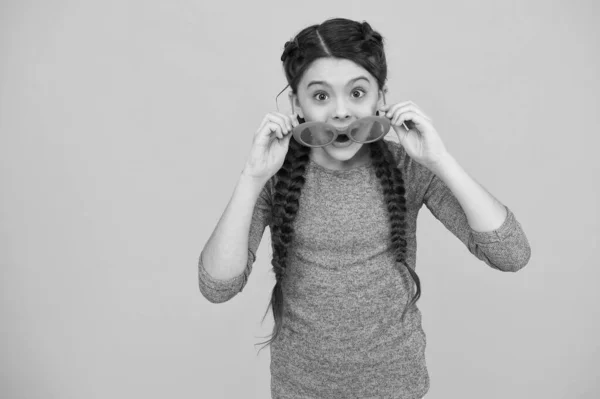 Méritent un super cadre. surpris jolie fille souriante avec coiffure à la mode. enfant insouciant fond jaune. Des émotions positives à la fête. Un gamin qui s'amuse. Portrait de fille heureuse dans des lunettes drôles — Photo