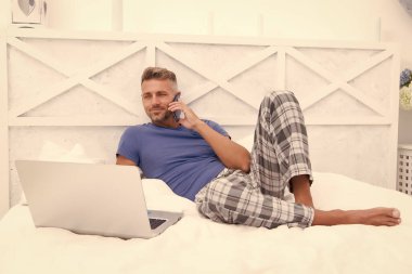 İnternette çalışıyorum. Adam dizüstü bilgisayarda çalışıyor. Online kurslar evde eğitim. İpuçlarını kilitle. Bir şeyler alıp internetten alışveriş yapmak. Adam yatakta telefonu kullanıyor. İletişim ve insan konsepti. Çevik iş. sabah titreşimleri