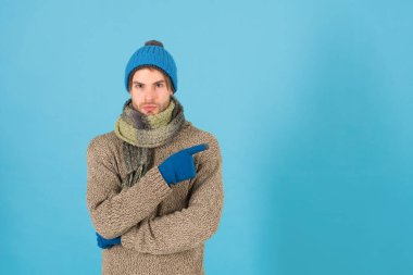 En iyi teklif burada. Tıraşsız yakışıklı adam mavi arka planda kış aksesuarları takıyor. Kış sezonu indirimi. Hippi, kış şapkası eşarbı ve eldiven ördü. Erkek güzeli. Alışveriş konsepti. Kıyafet dükkanı.