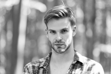 Sakallı, genç yüzlü, çekici bir adam. Teni ve şık saçları var. Yaz manzarasında sıradan bir tarzı var.