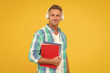 Ücretsiz yemek. Ses kursları. İngilizce öğreniyorum. Modern teknoloji. Ses kitabı konsepti. Dünya çapında bilgi erişimi. Ses kütüphanesi. Yakışıklı öğrenci kulaklık takıyor ve kitap tutuyor. Dil çalış