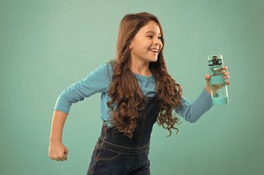 Biraz sıvı iç. Sağlıklı bir hayat. Sağlık ve su dengesi. Kızın elinde su şişesi var. Uzun saçlı kızın su şişesi var. Su dengesi kavramı. Güçlü ve sağlıklı çocuk.