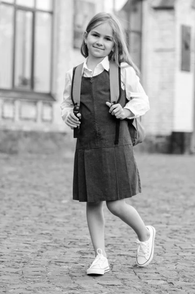 Elegante e elegante. Um miúdo fardado leva a mochila da escola. De volta ao material escolar. Roupa de escola. Vestido uniforme. Educação formal. 1 de Setembro. Olhar intemporal. Estilo retro, filtro vintage — Fotografia de Stock