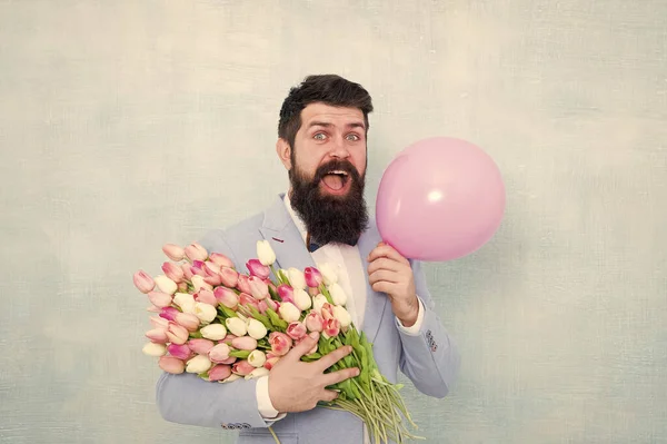 Spring mood. Love date. Gift bouquet. Present for spouse. Guy with air balloon. Birthday party. Bearded man hipster with flower bouquet. 8 march. Flowers for womens day. Bearded man with tulips