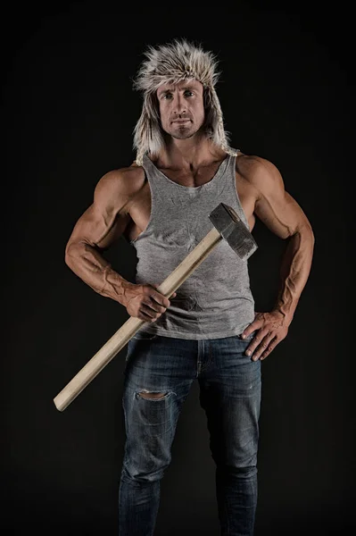 Atletizm işçisi çekiç aletini güçlü kol pazılarıyla tutuyor. Sıradan giyimli, siyah arka plan, madenci. — Stok fotoğraf