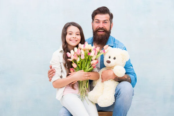 Pappa och flicka barn omfamna med våren tulpan blomma bukett och nalle leksak, barn dag — Stockfoto