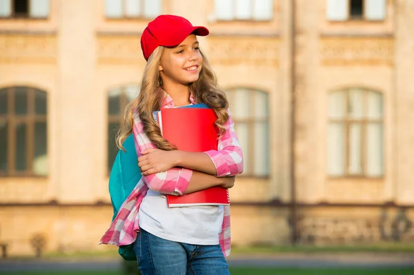 Ευτυχισμένο παιδί σε casual στυλ μόδας κρατήσει βιβλία μελέτης μεταφέρουν σχολική τσάντα με σκεπτική ματιά σε εξωτερικούς χώρους, το μέλλον, αντίγραφο χώρο — Φωτογραφία Αρχείου