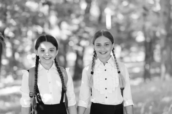 Gelukkige tiener kinderen dragen rugzak. terug naar school. kleine schoolmeisjes die in het voorjaar lopen. Gelukkige kinderdag. Kindergeluk. twee zussen in schooluniform buiten. klaar voor vakantie — Stockfoto