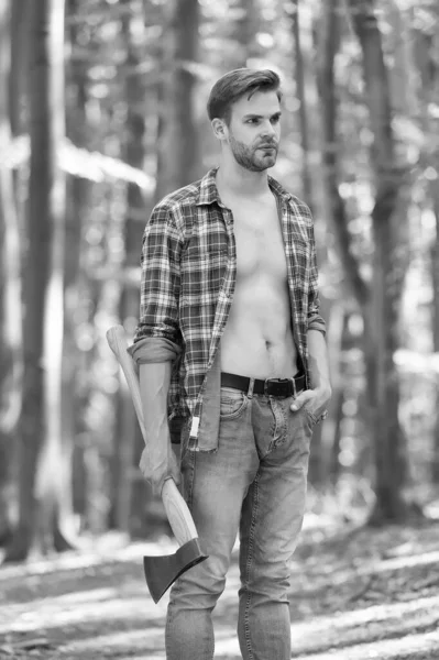 Every man needs some time for himself. Handsome guy hold axe in woods. Unshaven guy with sexy torso in open shirt. Lumberjack style. Summer vacation. Natural landscape. Traveling and wanderlust — Stock Photo, Image