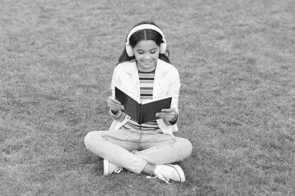 Sois un bon acharné. journée de la connaissance. future éducation scolaire. adolescent fille avec livre sur l'herbe verte. jolie enfant petite fille lire le livre. étudier la littérature pour les enfants. les nouvelles technologies dans la vie numérique — Photo