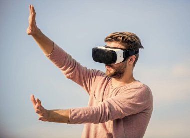 Yeni deneyimlerin tadını çıkarıyorum. Kendi işini kur. Sanal oyun oyna. Seksi adam gökyüzü arkaplan gözlüğü. Dijital dünyadaki erkek gerçekliği. VR kulaklığı kullan. Maço adam kablosuz VR gözlük takıyor..