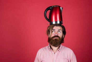 Sıradan bir adam modern teknolojiyi günlük hayatta kullanır. Bıyıklı hippi suyu kaynatıyor. Erkek ev idaresi. Çay içme konsepti. Gömlekli sakallı adam elektrikli su ısıtıcısı tutuyor. Kopyalama alanı