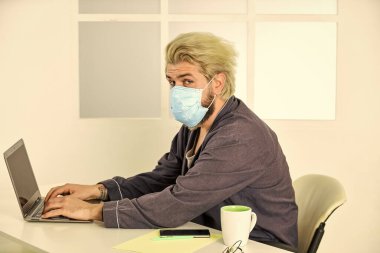 Uzaktan kumanda. Sınırlı hastalık yayılıyor. Uzaktan iletişim. Sosyal uzaklık. Çevrimiçi çalışan serbest çalışan bir adam. Adam internette sörf yaparken maske takıyor. Uzaktan kumanda. Çevrimiçi topluluk. Coronavirus karantinası