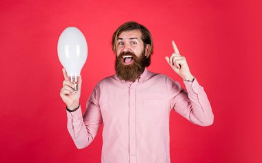 Elektrik ve aydınlatma. Enerjini sakla. Yenilik. Ampul tutan mutlu sakallı adam. yaratıcı fikir. Yeni fikirden esinlendim. Yetişkin vahşi hippi beyin fırtınası. enerji tasarrufu lambası