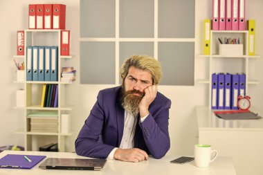 Yakışıklı adam fincandan kahve içiyor. İşadamı ofisinde oturuyor. Bilgisayarda çalış. Dizüstü bilgisayardaki yorgun profesyonel iş adamı. İş adamı şık günlük kıyafetler giyiyor.