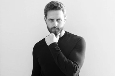 Sakal eğilimi devam edecek mi? Ciddi bir olgun adam tıraşsız çeneye dokunur. Beyaz sakallı adam. Sakal bakımı rutini. Cilt ürünleri. Saç bakım kozmetiği. Berber dükkanı. Kuaför salonu.