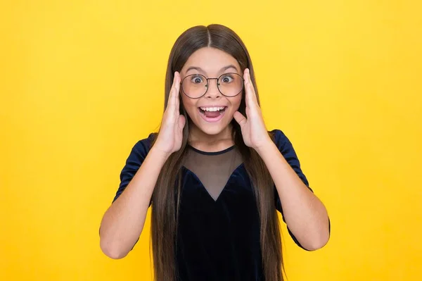 Criança menina inteligente espantado com cabelos longos e óculos no fundo amarelo, visão — Fotografia de Stock