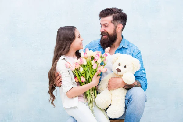 С праздником. отец и дочь с цветами и игрушками. Девочка-подросток и папа держат букет тюльпанов. 8 марта или женский день. весенний подарок. любовь и семейные ценности. Счастье. счастливый семейный день — стоковое фото