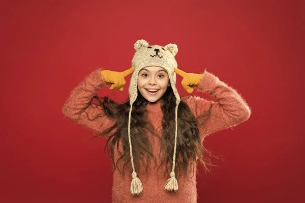 冬服だ。小さな子供はニット帽を着用する。暖かくして。女の子の冬のファッションアクセサリー。小さな子供の長い髪は赤い背景の帽子を着用する。かわいいモデルは冬のスタイルをお楽しみください。テディベア。可愛いクマさん — ストック写真