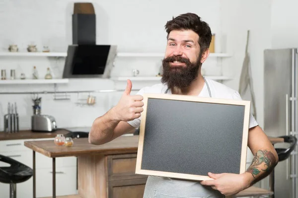 Brodaty hipster człowiek trzymać tablicę dla miejsca kopiowania i pokazać kciuk w górę, menu — Zdjęcie stockowe