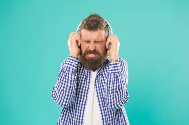 Sesi kıs. Mutsuz hipster dinleme kitabı. Kulaklıkta yüksek sesle konuşan sakallı adam..