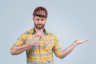 İnşaat kasklı yakışıklı ustabaşı ve inşaat alanında kareli gömlek. Ürün sunumu, fotokopi alanı, en iyi servis.