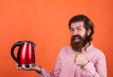 Bu en iyisi. Sakallı hippi ev aletleri kullanır. Mutfak konsepti Bıyıklı vahşi yakışıklı adam çay içiyor. Olgun koca elektrikli su ısıtıcısı tutar. Hayattaki modern teknoloji