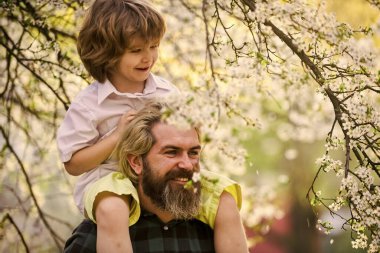 Gelmiş geçmiş en iyi baba. Çocuk babasıyla eğleniyor. Mutlu bir aile. Doğada yaşayan küçük bir çocuk ve baba. İlkbahar. Hippi bebeği sırtında taşıyor. Sakallı zalim adam, iyi baba. Babalar Günü. Baba ve oğul.