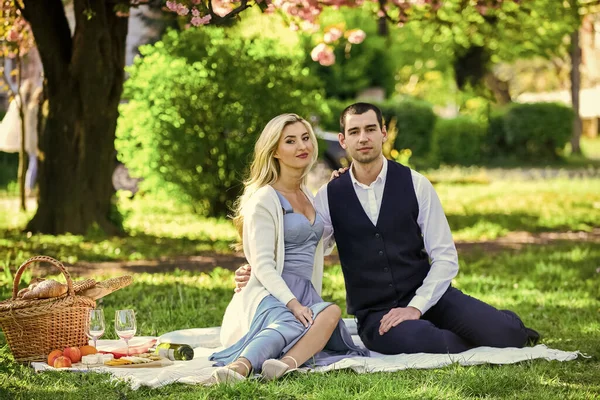 Casal apaixonado curtindo piquenique e comida ao ar livre. Pessoas bonitas apaixonadas namoro. Encontro de primavera. Casal relaxante no prado verde com cesta de piquenique. Encontro romântico. Celebra o amor. Estilo vintage — Fotografia de Stock