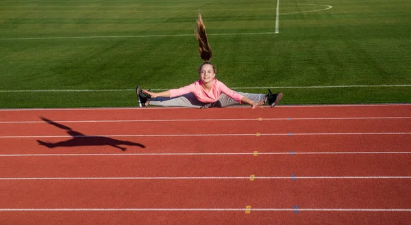 Menina adolescente pulando em dividir ao ar livre na pista de corrida estádio, energia — Fotografia de Stock