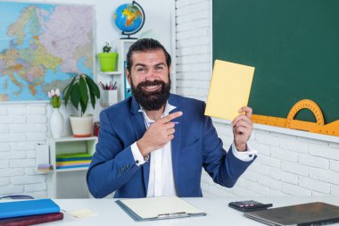 Sakallı ve bıyıklı bir adam üniversitede ya da okulda iş adamı ya da öğretmen gibi görünüyor.