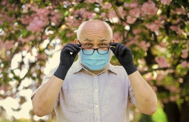 Dışarıda maskeli ve eldivenli kıdemli bir adam var. Yaşlılara nasıl yardım edileceğini. Özellikle yaşlılar enfeksiyon kaptıysa risk altındalar. Yaşlandıkça bağışıklık sistemi enfeksiyonlarla mücadelede daha az etkili oluyor.