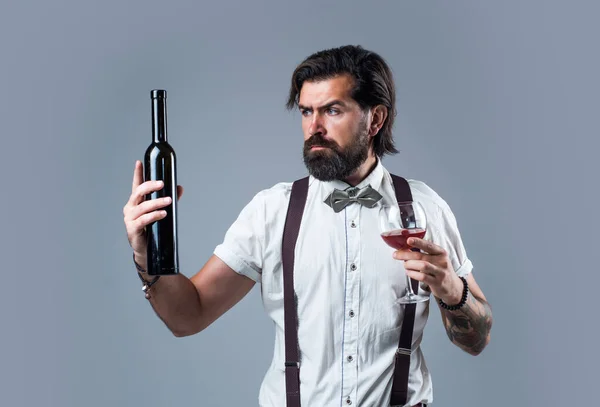 wine delivery service. drinking wine glass. bearded man in suspenders drink red wine. elegant businessman wear bow tie for formal event. sommelier tasting alcohol. bartender. stylish male barman