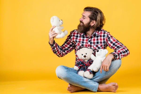 Hombre barbudo brutal usar camisa a cuadros con barba exuberante y bigote con peluche juguete oso, tienda de juguetes —  Fotos de Stock