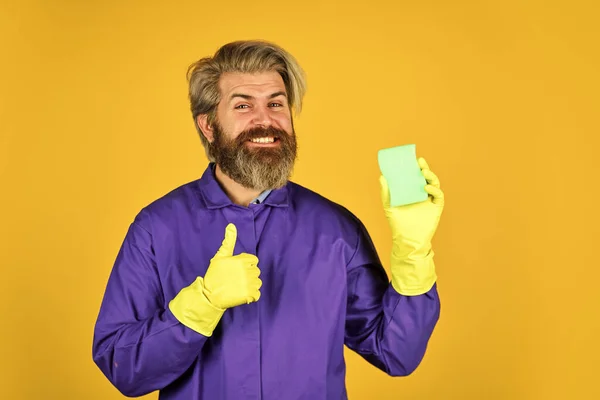 Úspěšný správce domu. pomocí houby na čištění. Manžel čistého domu. hygiena a čistota. vousatý muž nosí gumové rukavice. zralý školník v uniformě žluté pozadí. jarní úklid — Stock fotografie