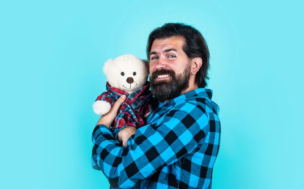 Macho celebración cumpleaños o regalo de San Valentín. hombre barbudo con camisa a cuadros sostienen oso de peluche. chico casual expresar emociones de amor. feliz hipster con bigote jugar juguete —  Fotos de Stock