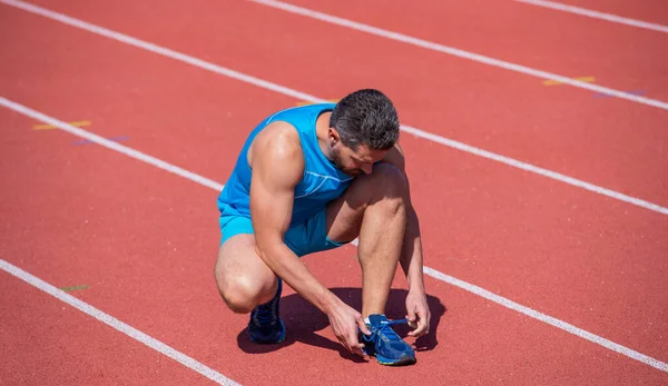 Man tie shoelaces after exercise on stadium. fitness gym outdoor. muscular athletic guy training. sport. male fitness fashion. sportsman has a break. athlete need relax — Stock Photo, Image