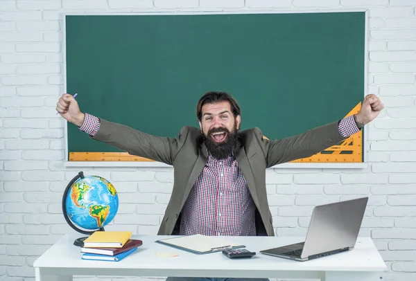 mature bearded man teacher in costume sit in school classroom with geography globe map, vacation