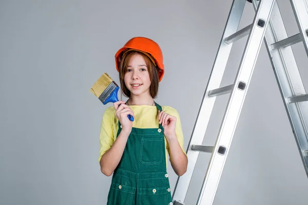 Ребенок строит. Инженер подросток строитель. Международный день трудящихся. художник на стремянке. Девушка в шлеме играет строителя. строительство и ремонт. Думаю, я могу тебе помочь. — стоковое фото